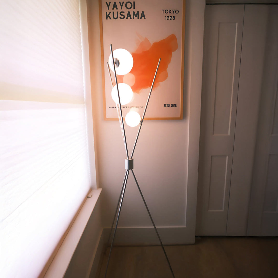 Modern floor lamp with a framed Yayoi Kusama artwork on the wall.