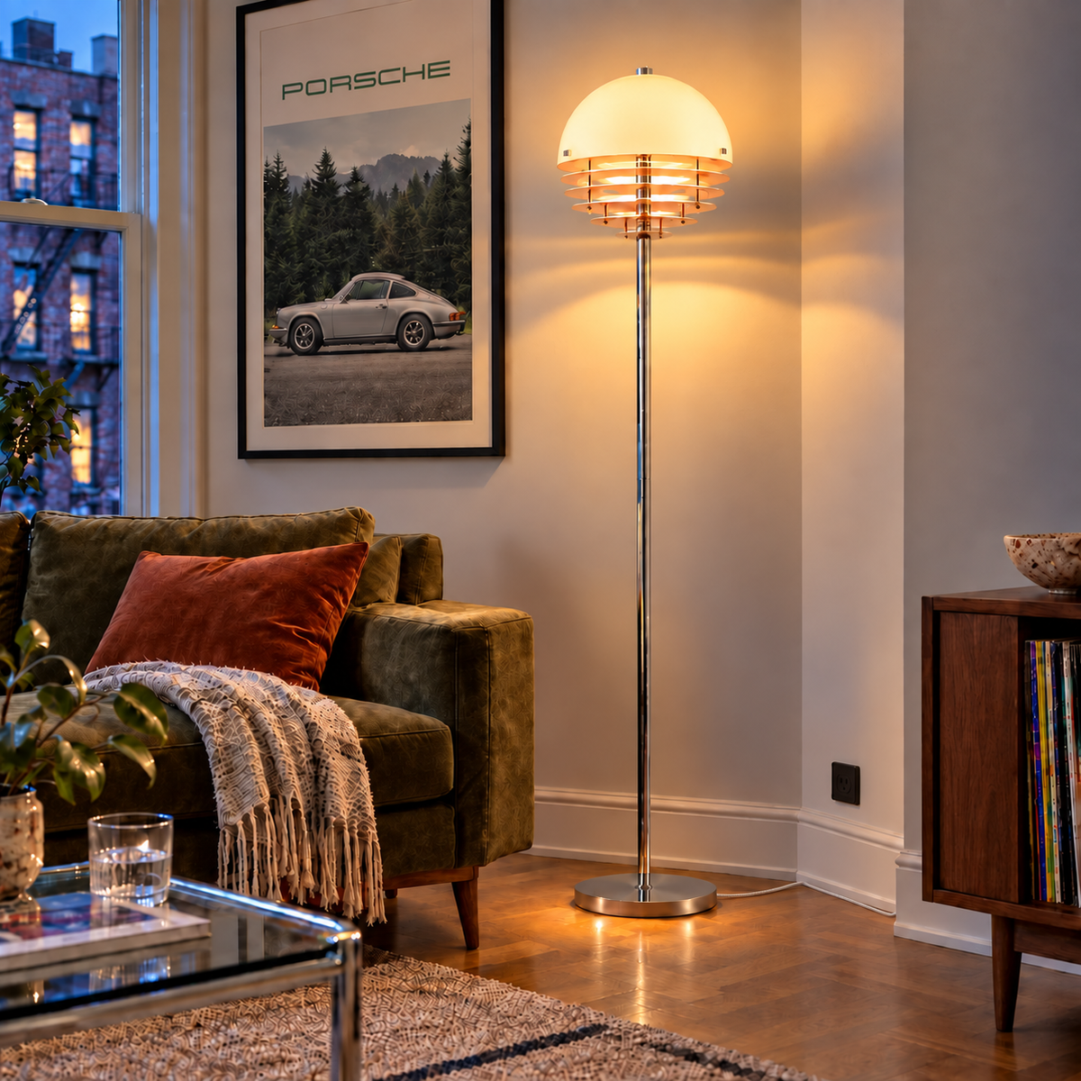 Aperol floor lamp illuminating an evening living room with Porsche artwork, olive seating and a white woven cord tucked behind the brown record cabinet.